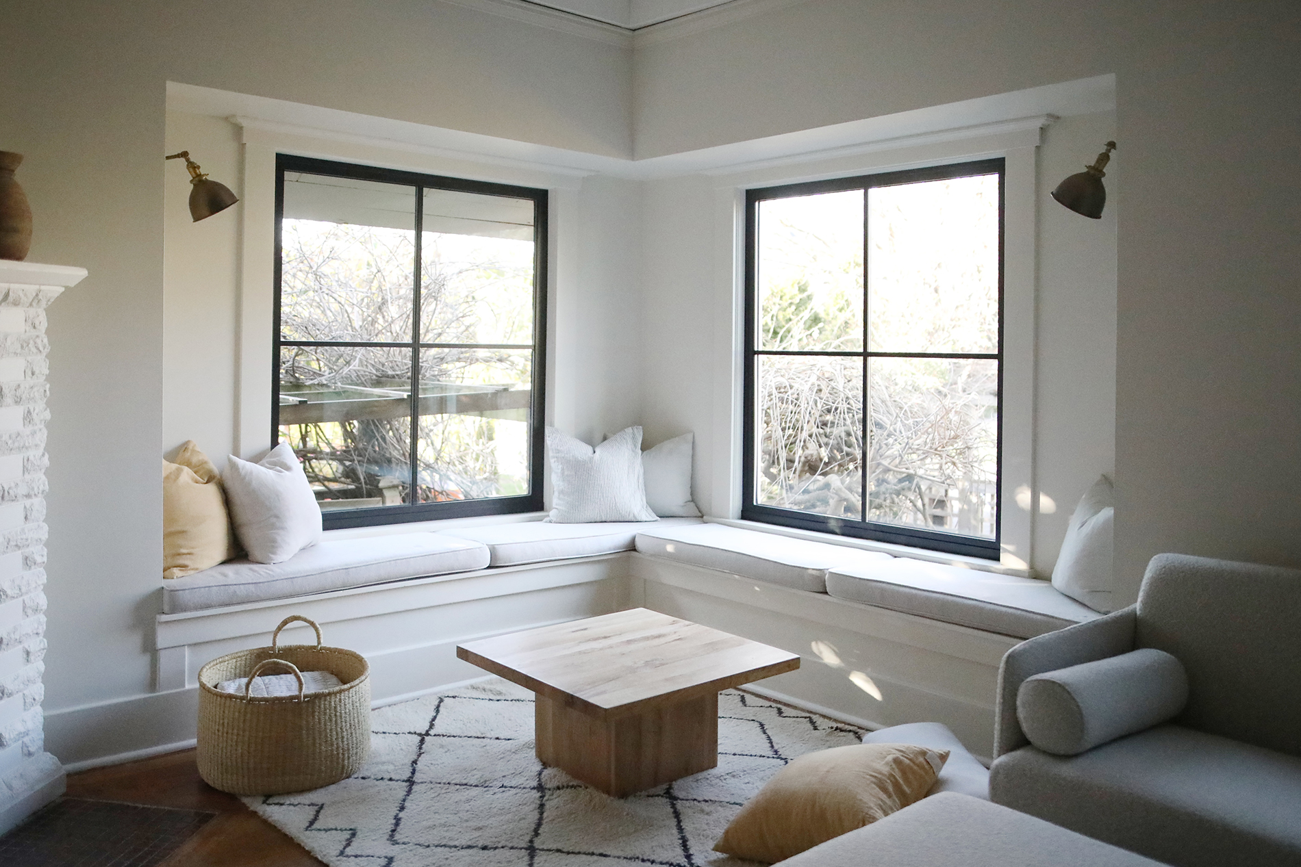 A comfortable seating area interior with accent pillows for additional décor and large black vinyl windows with grids. 