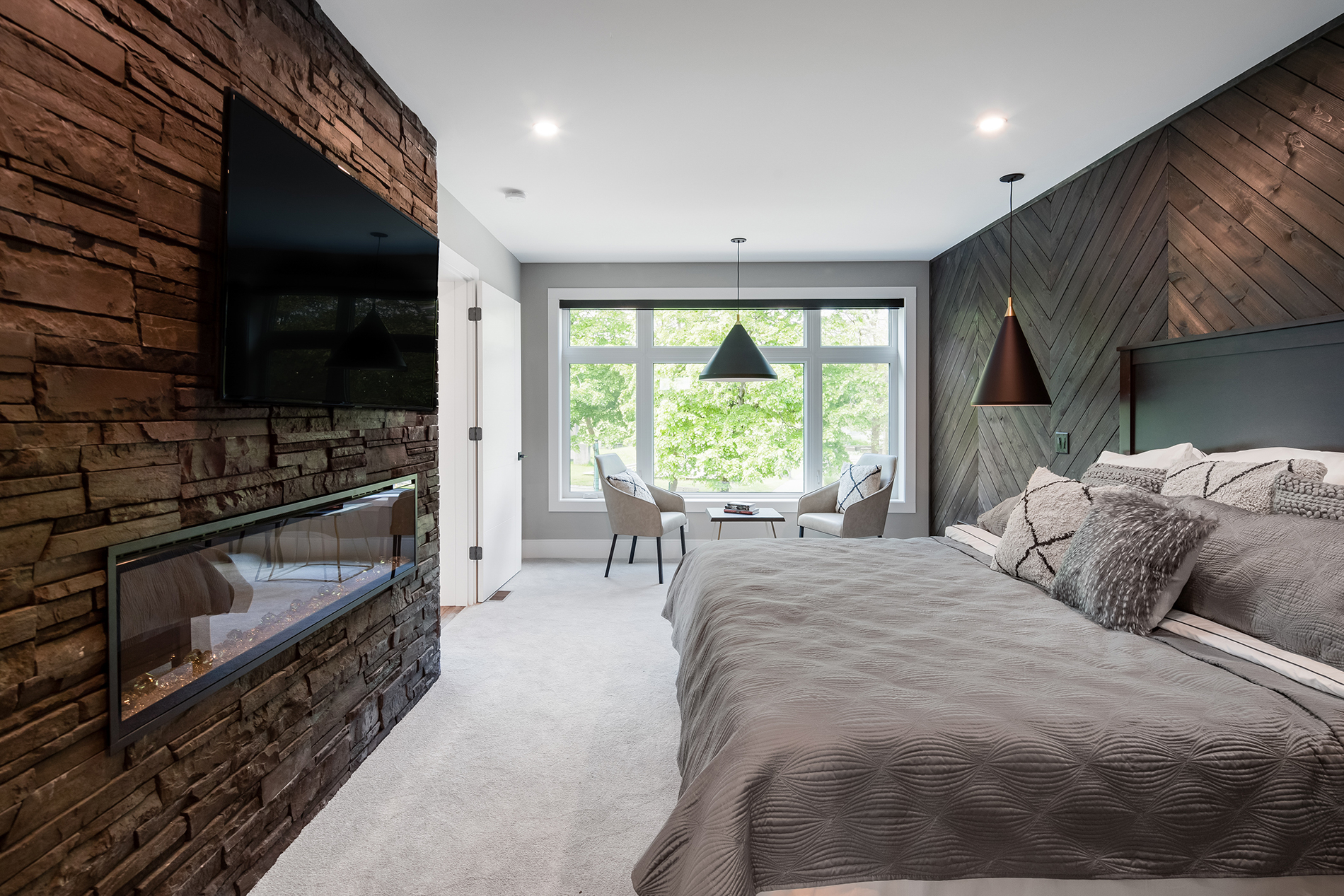 Spacious bedroom with dark colour tones and warm decor styling that is paired with large classic white vinyl windows